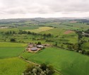 Aerial view of multiple different farm fields with farm buildings in the center.